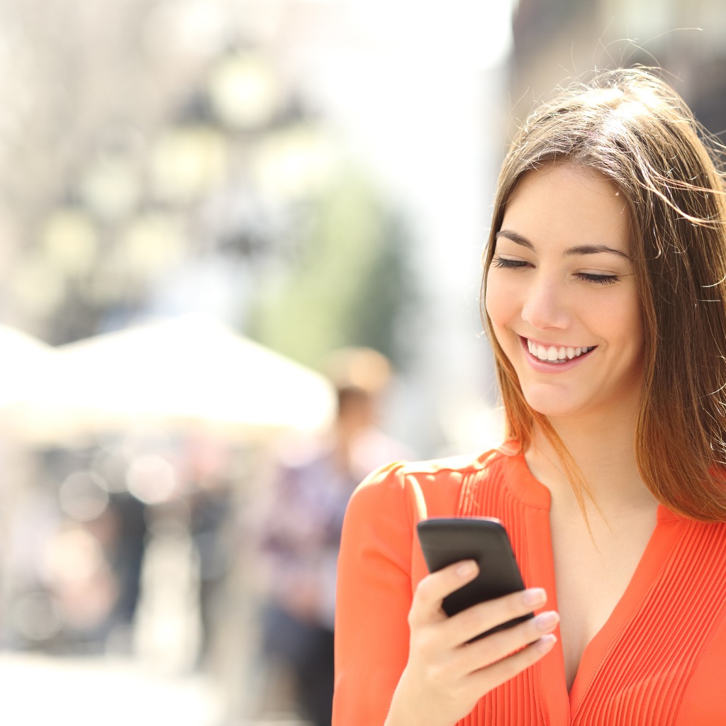 Woman smiling, holding and looking at cellphone